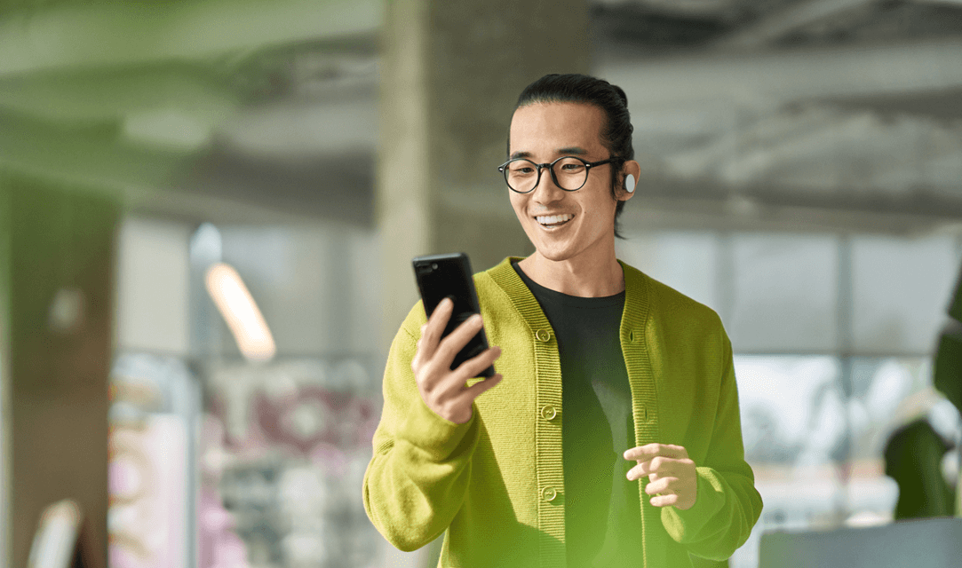 A smiling man looking at his Access mobile app on his smartphone